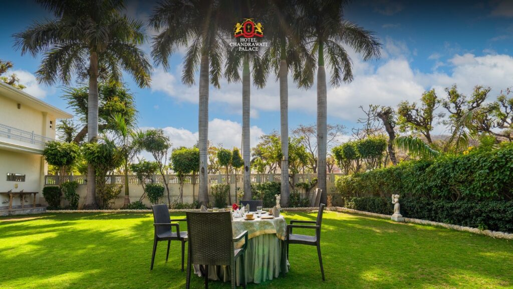 Outdoor garden dining setup surrounded by palm trees at Chandrawati Palace.